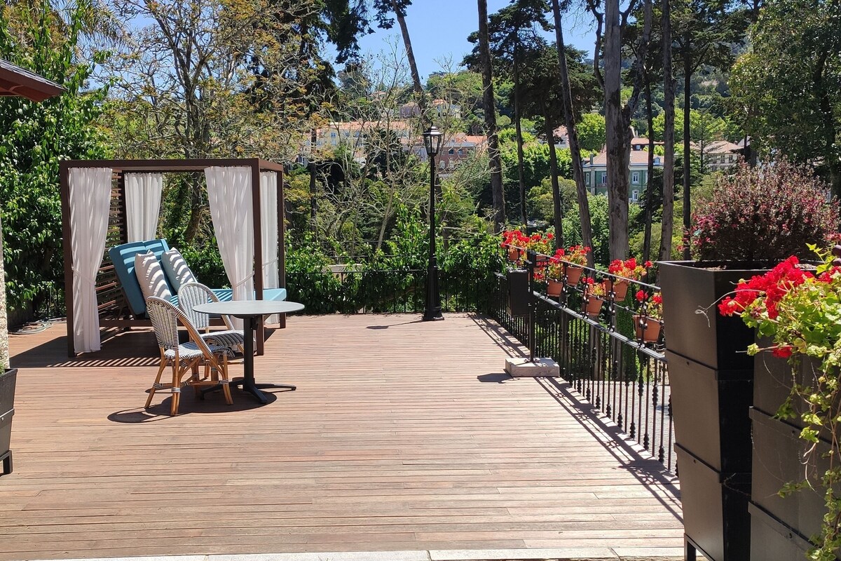 A wooden deck with a pergola, outdoor seating, and potted plants.