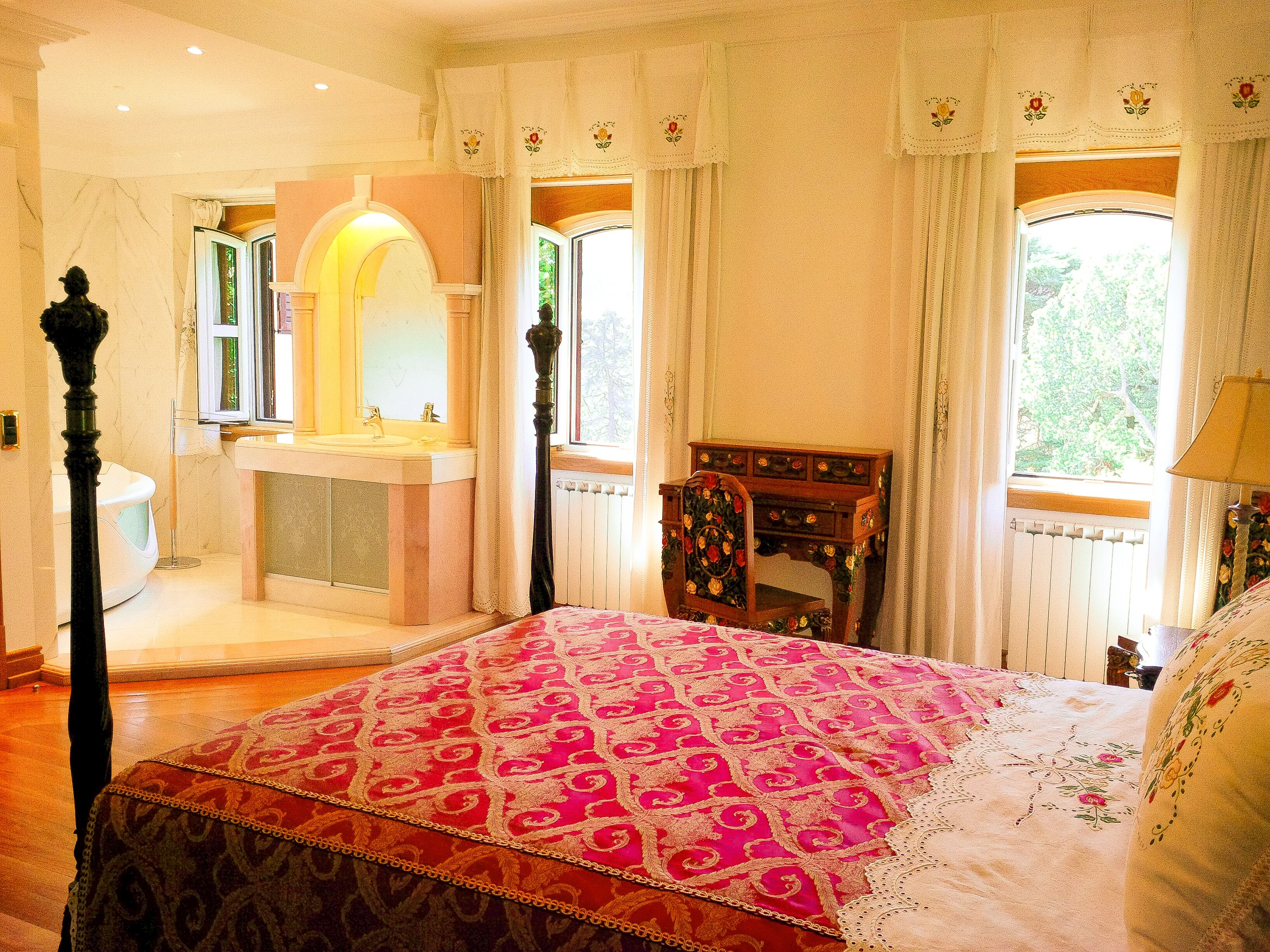 Un dormitorio con una cama grande, una mesita de noche de madera, un aparador y una ventana con cortinas.