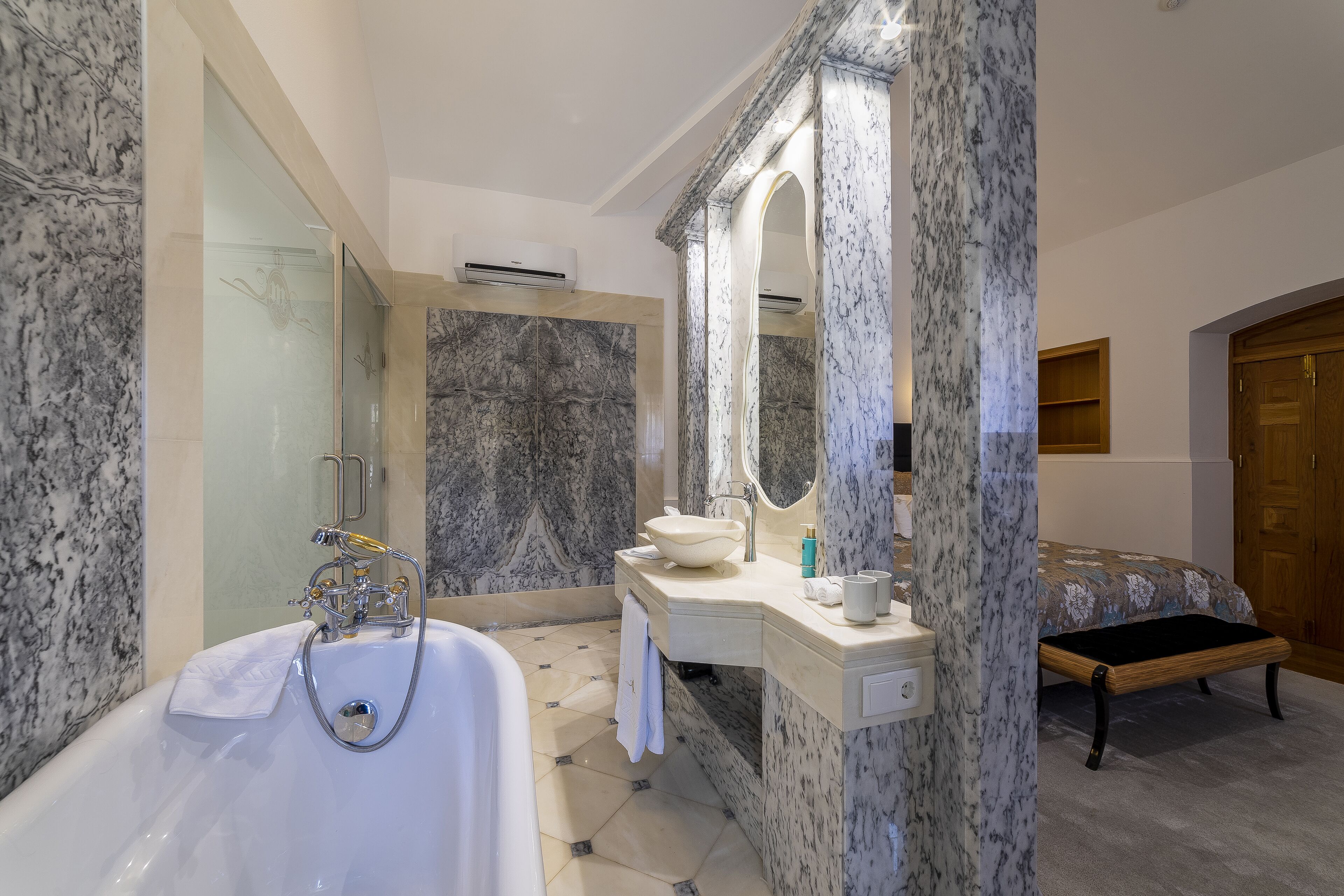A modern bathroom with a marble sink, a bathtub, and a large mirror.
