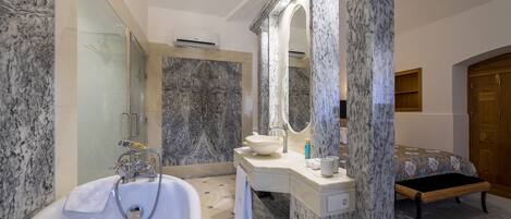 A modern bathroom with a marble sink, a bathtub, and a large mirror.