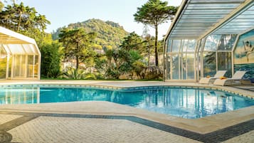 Una piscina cubierta, una piscina al aire libre, sombrillas, tumbonas