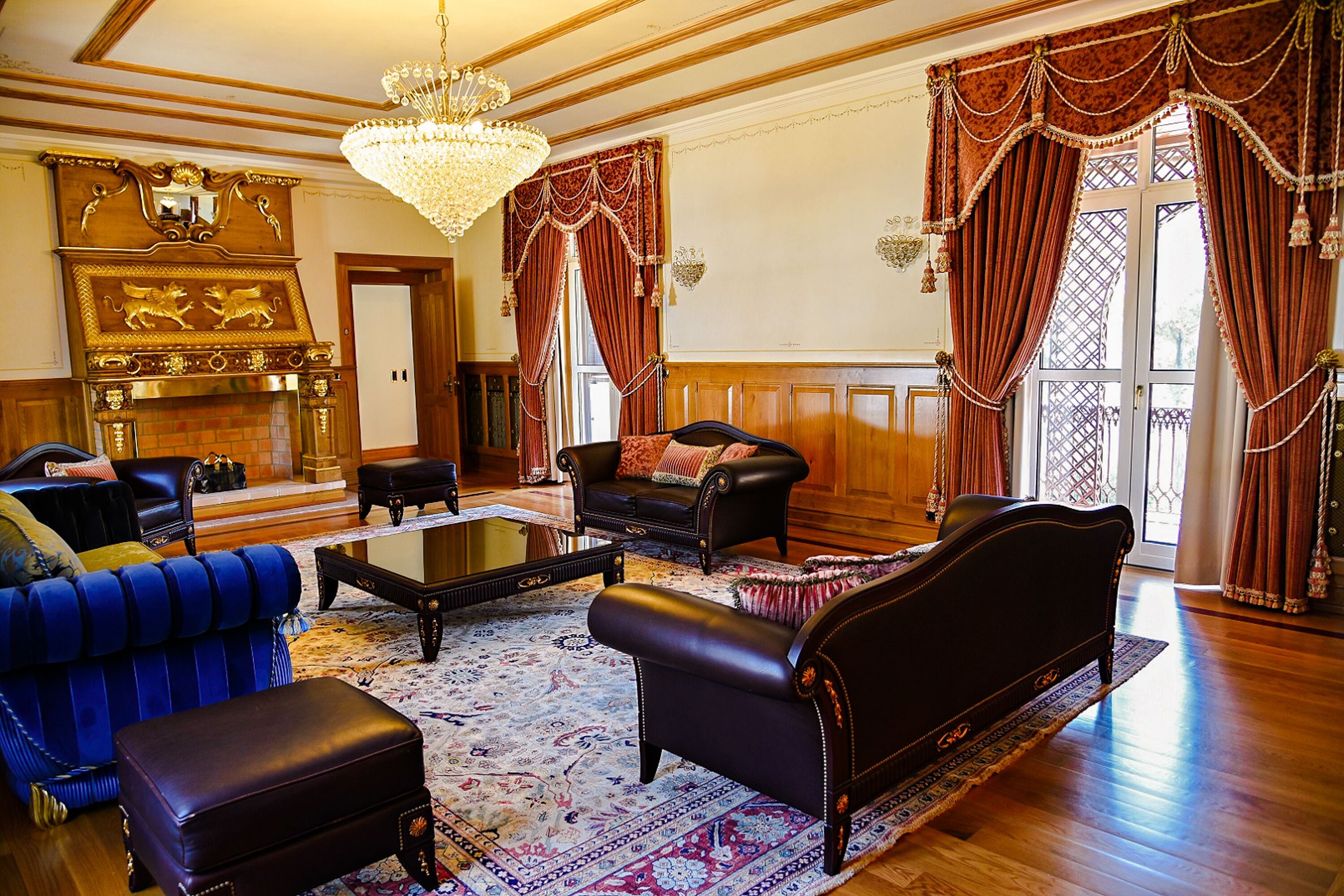 A spacious living room with a fireplace, leather sofas, a coffee table, and a chandelier.