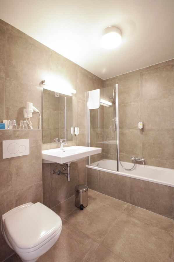 A modern bathroom with a toilet, sink, and bathtub. - Hotel Lepelbed Melle (Melle)