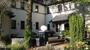 A courtyard with a white building, a stone bench, and a variety of plants. - Hotel Lepelbed Melle (Melle)