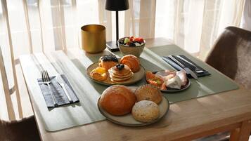 A breakfast setting with pastries, fruits, and a bowl of yogurt parfait on a table with a placemat.