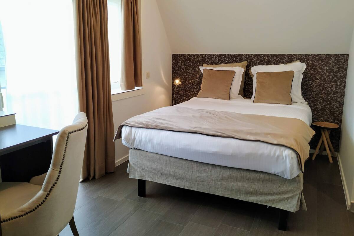 A bedroom with a bed, a desk, and a chair.