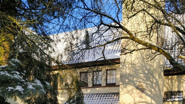 A snow-covered courtyard with a building featuring a tiled roof and a wooden door. - Hotel Lepelbed Melle (Melle)