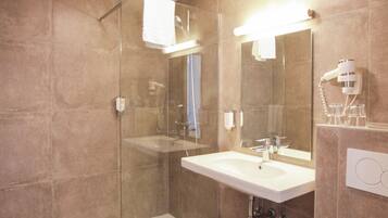 Ein modernes Badezimmer mit einer gläsernen Dusche, einem weißen Waschbecken und einer Toilette.