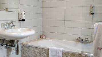 A bathroom with a white sink, a bathtub, and a mosaic floor.