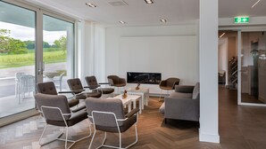 Un área de descanso moderna con asientos, un televisor de pantalla plana y vistas al exterior.