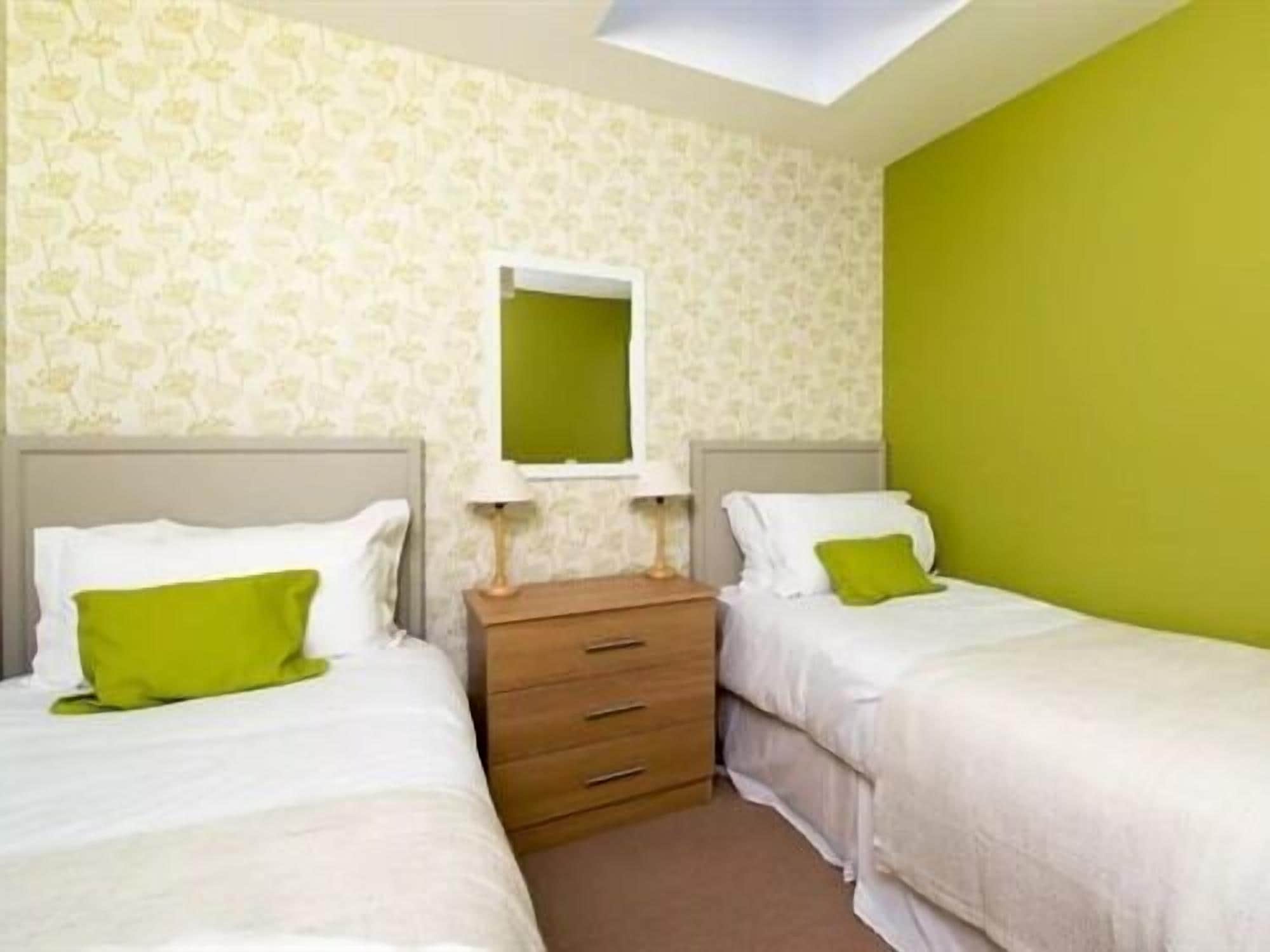 A room with two beds, a wooden dresser, and a skylight.