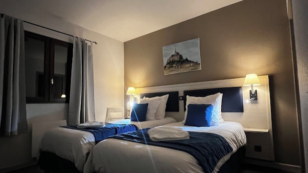 Habitación de hotel con una cama grande, dos mesitas de noche, una ventana con cortinas, un cuadro colgado en la pared y una lámpara en el techo.