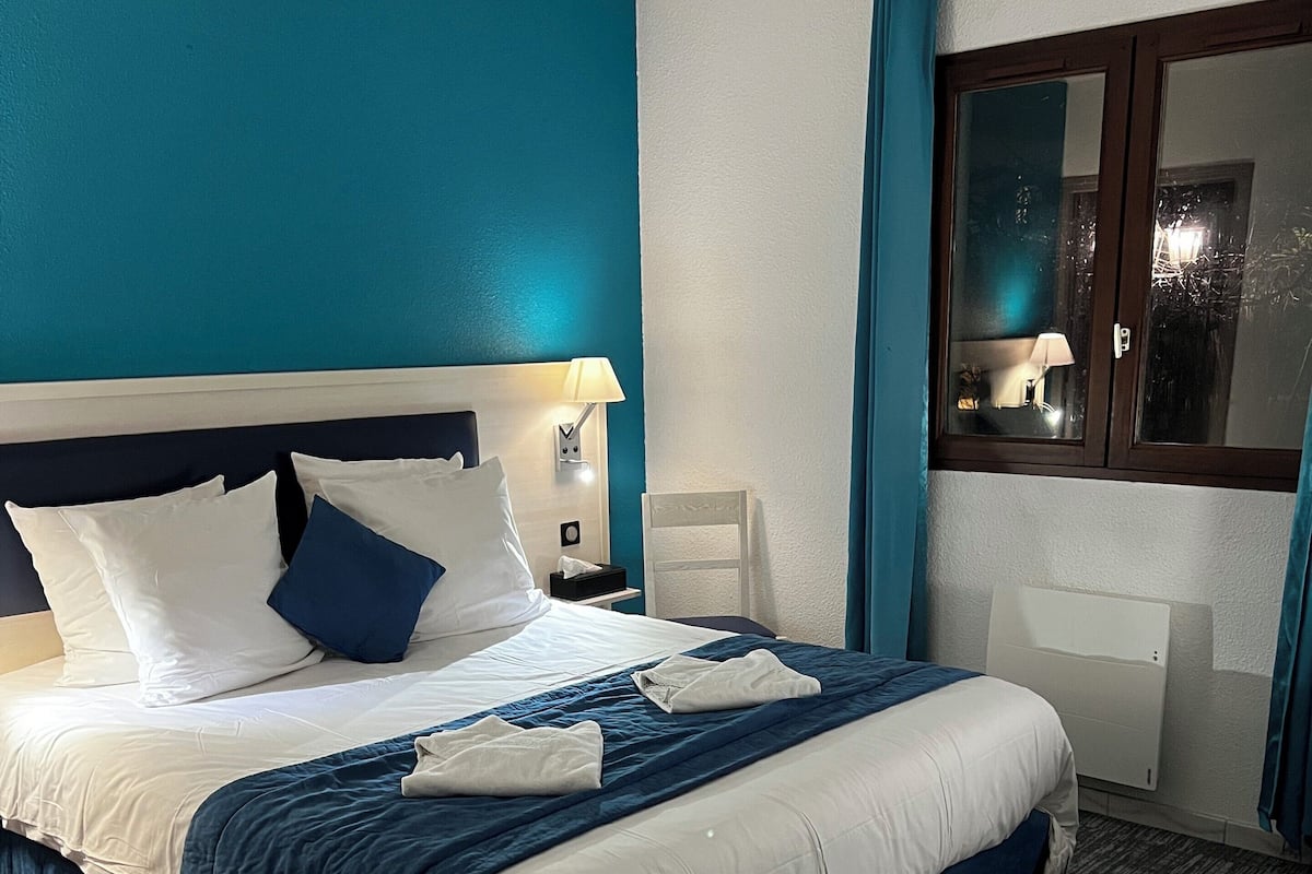 A hotel room with a large bed, a desk, and a window.
