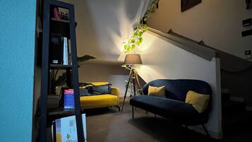 Una sala de estar acogedora con un sofá, una mesita y una estantería.