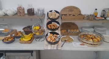 Um buffet de café da manhã com diversos alimentos e utensílios.