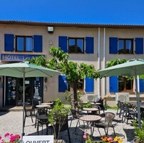 Um hotel com área externa para sentar, persianas azuis e uma placa com a inscrição "HOTEL Les Arcs".