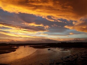 A sunset over a beach with a pier extending into the water.