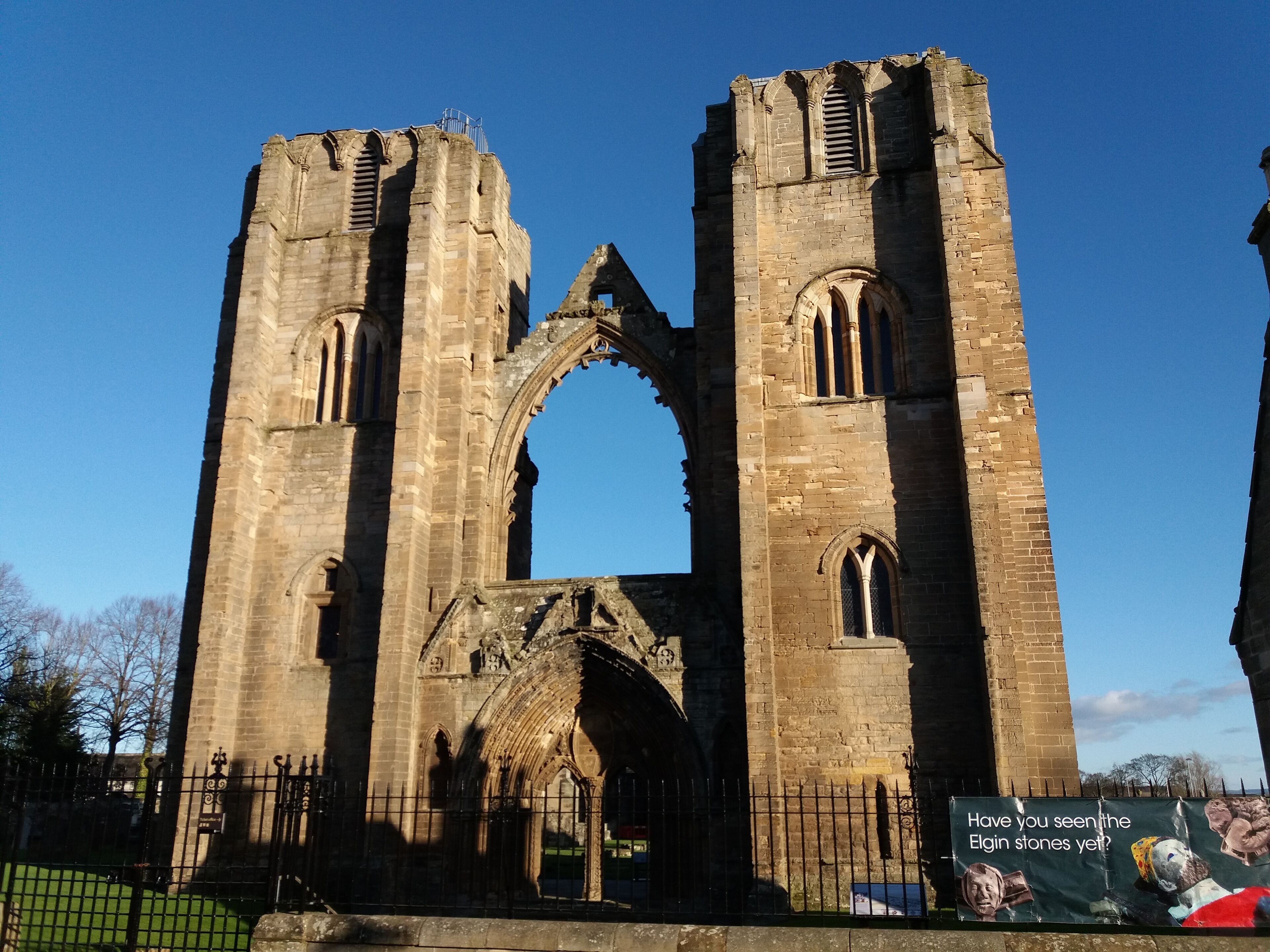 The ruins of a large stone structure with two tall towers and a central archway.