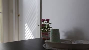 A dark wooden table with a white plate, a green and white vase with flowers, and a white box with a red ribbon.