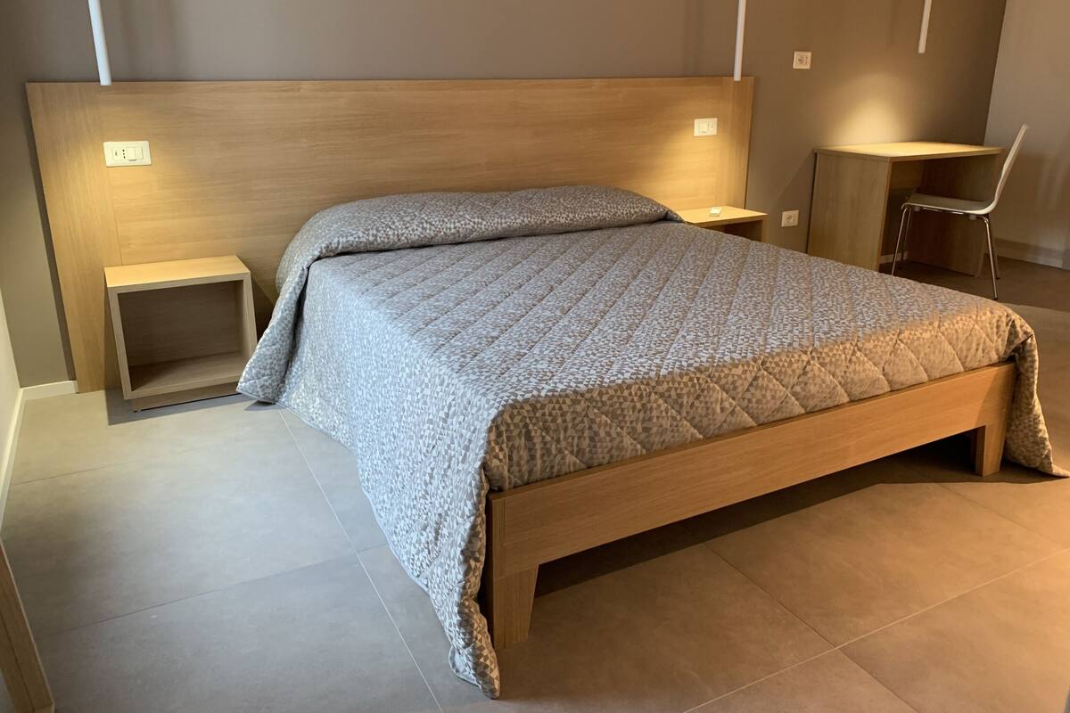 Une chambre à coucher moderne avec un lit en bois, des tables de chevet et une chaise.