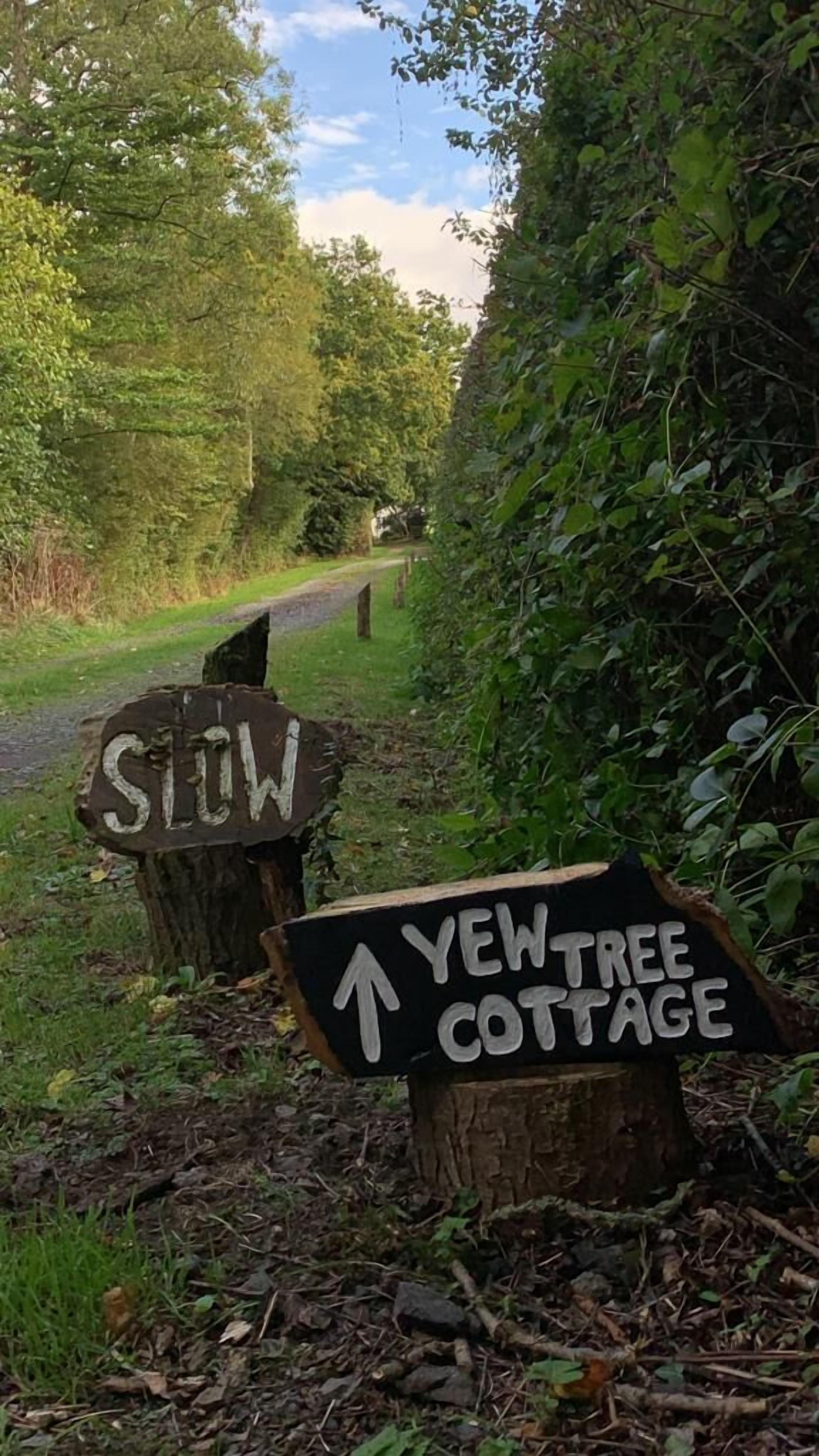 Dos senyals de fusta amb lletra blanca, un amb la inscripció “STIW” i l'altre indicant “YEWTREE COTTAGE”.