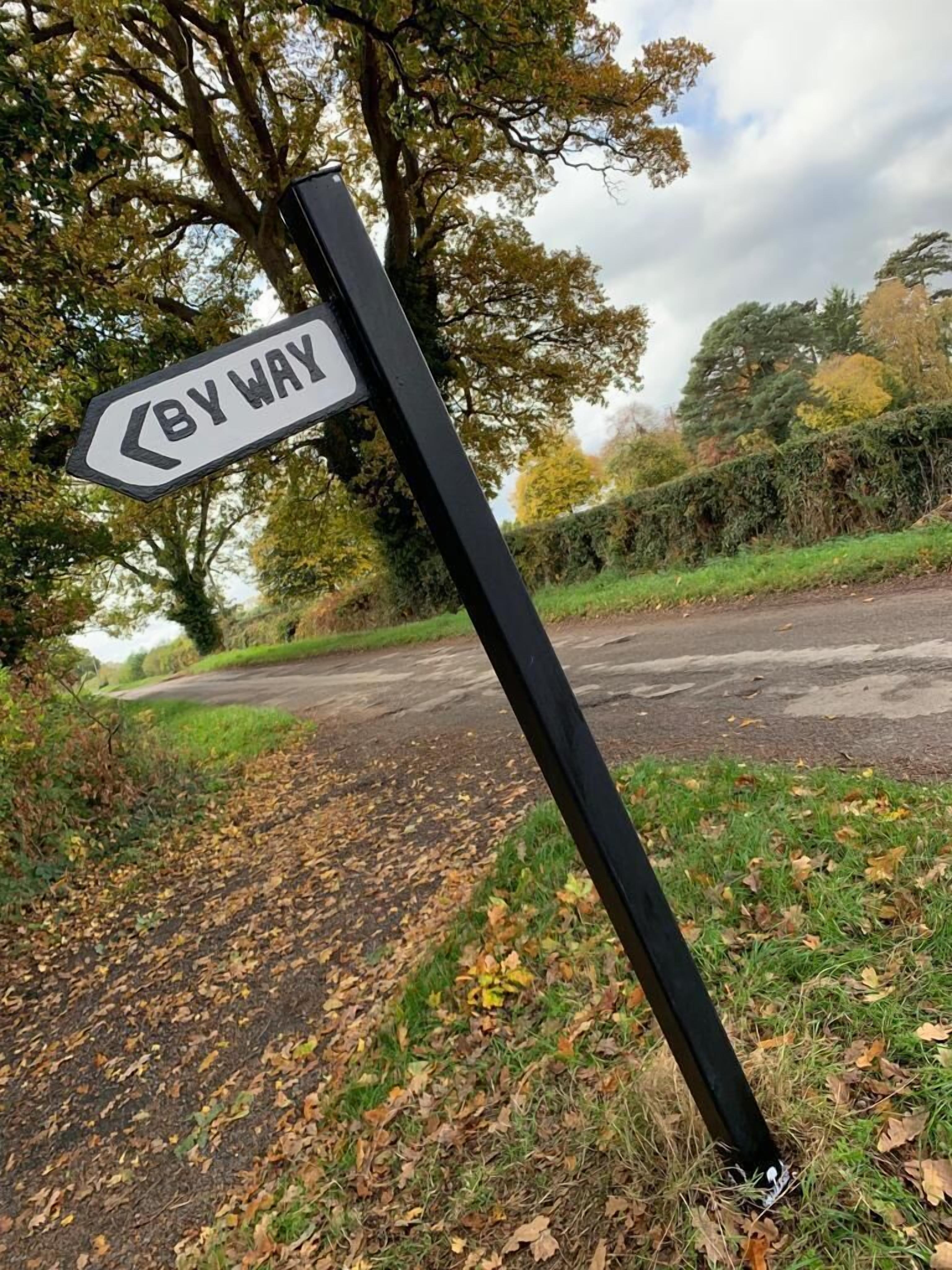 A 'BY WAY' sign on a roadside.