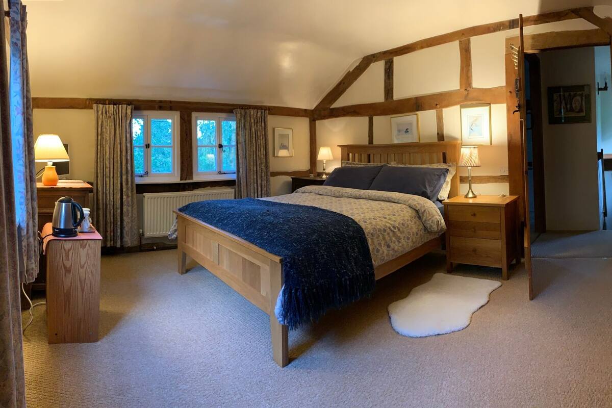 Une chambre à coucher avec un lit en bois, des tables de chevet, un radiateur et une fenêtre avec des rideaux.