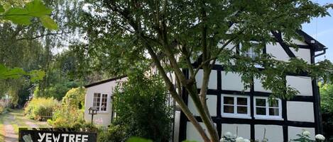 A traditional Tudor-style cottage with a garden path leading to the entrance.