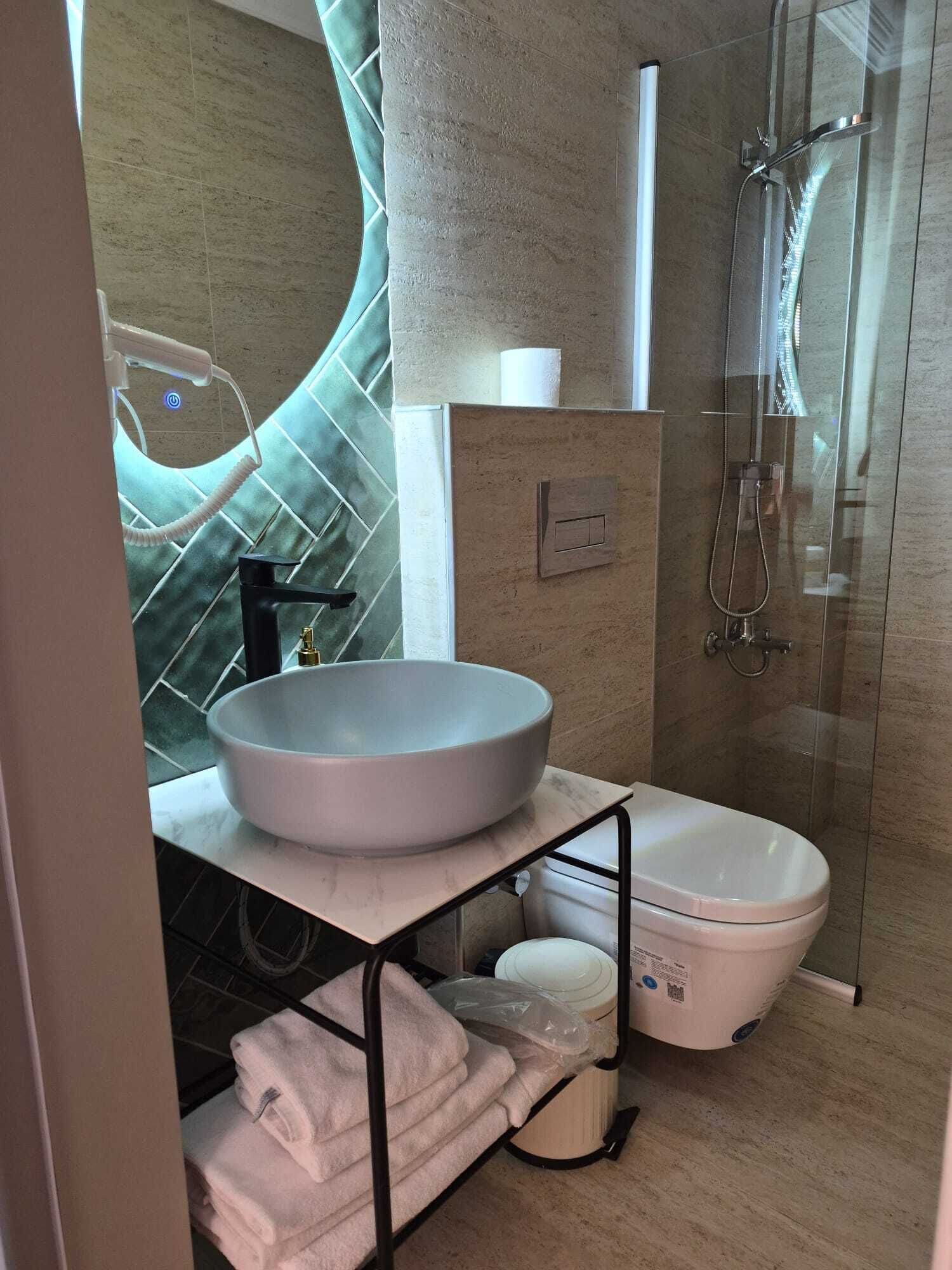 A modern bathroom with a large vessel sink, a toilet, and a glass-enclosed shower.