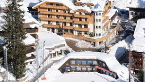 Un bâtiment enneigé, doté de nombreux balcons, sur lequel on peut lire l’inscription « MADONNA DI CAMPIGLIO ».