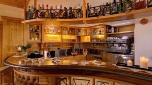 Un espace bar avec des étagères en bois remplies de bouteilles, un comptoir avec des verres et une machine à café.