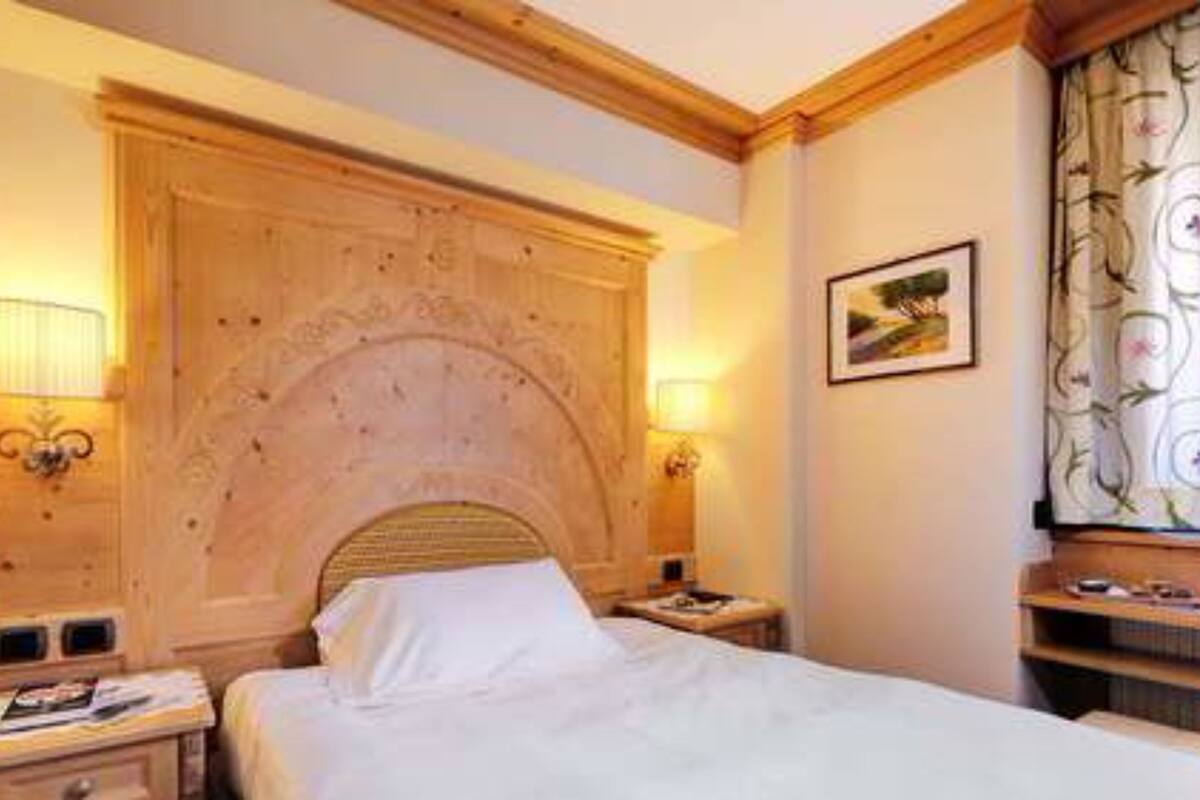 A hotel room with a wooden headboard, a bed, two bedside tables, and a nightstand.