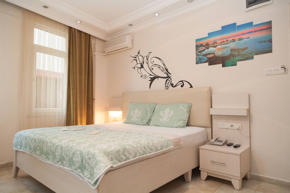 A bedroom with a bed, nightstand, and wall art.