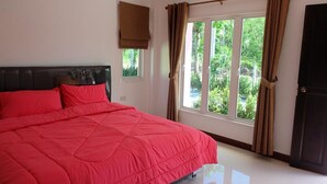Un dormitorio con una cama grande, una ventana con cortinas, un ventanal pequeño y una puerta.
