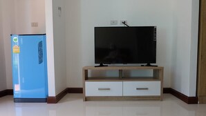 Una sala de estar moderna con una televisión de pantalla plana sobre un mueble de madera, un refrigerador azul y un sofá blanco.