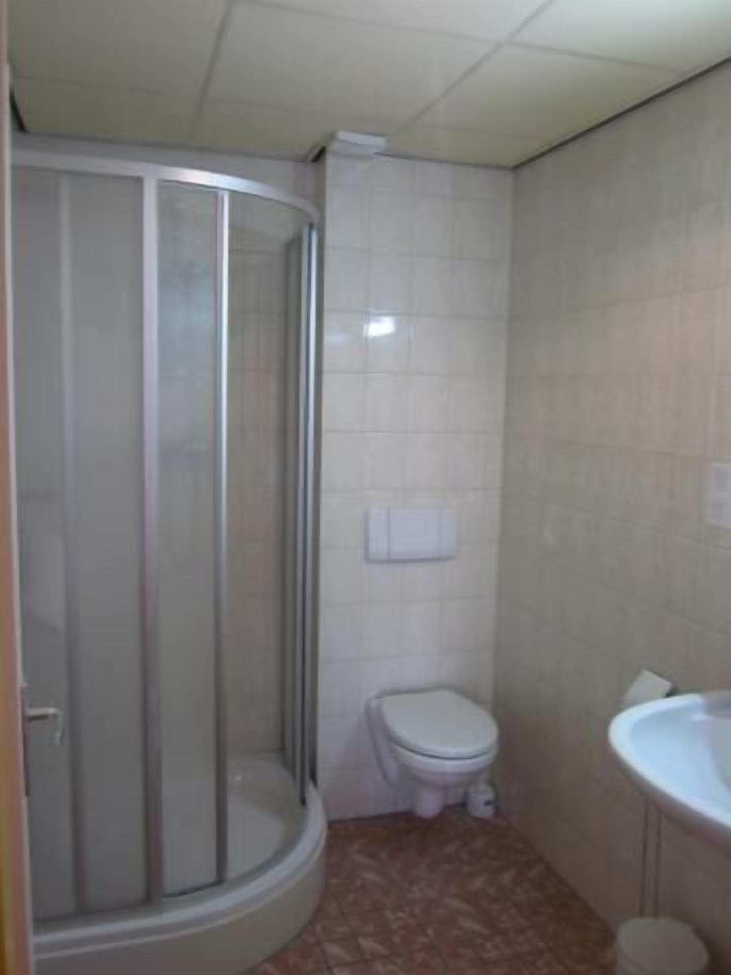 A bathroom with a shower enclosure, toilet, and sink.