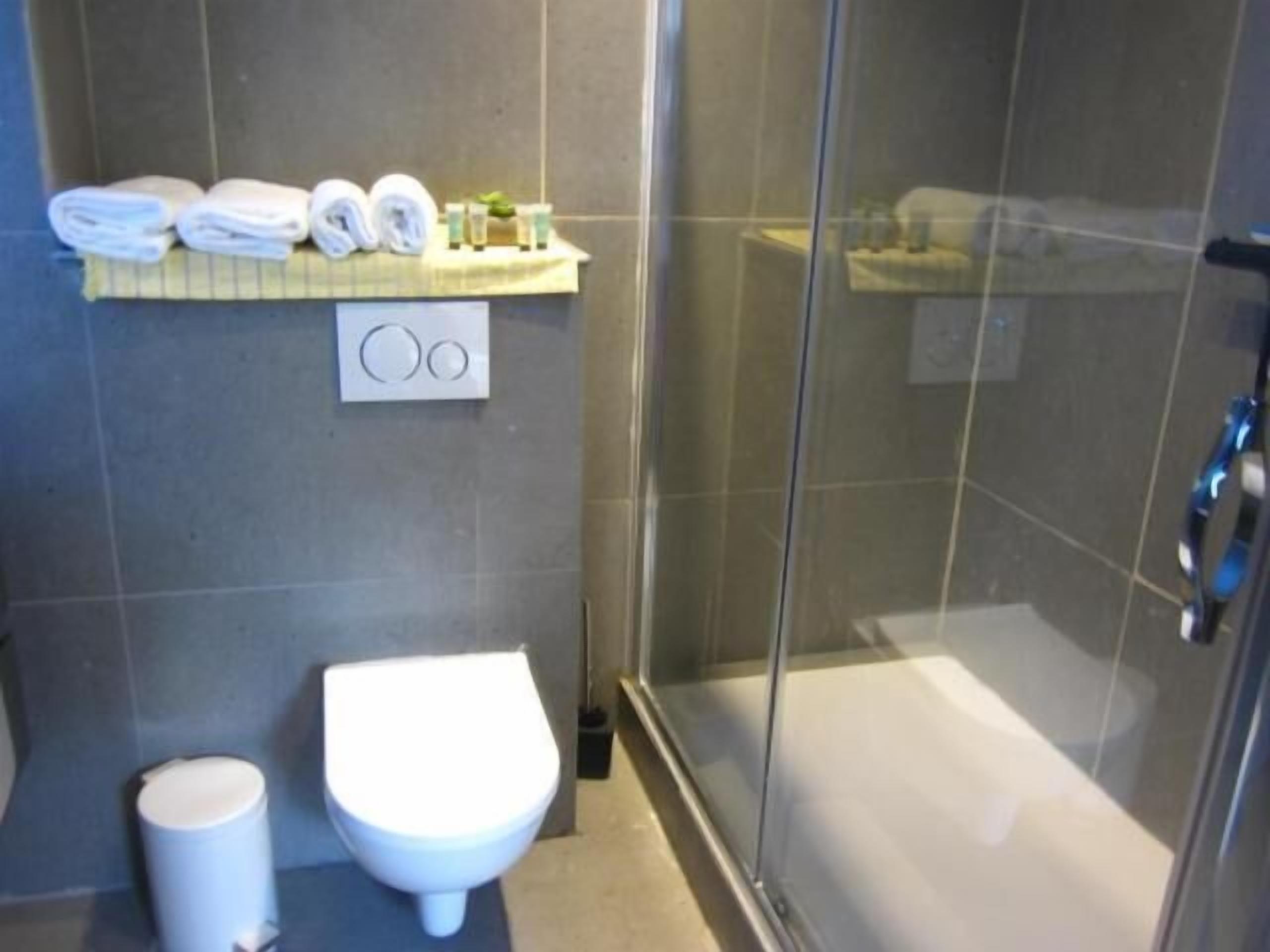 Un baño con inodoro, lavamanos y cabina de ducha de vidrio.