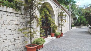 A stone wall with potted plants and an arched doorway. - A' Cunziria (Vizzini)