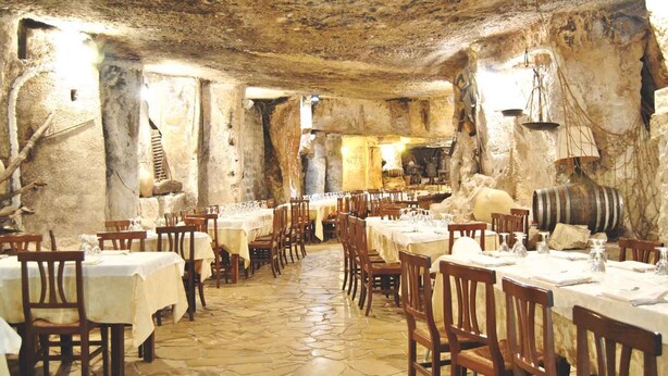 A restaurant with stone walls and tables set for dining. - A' Cunziria (Vizzini)