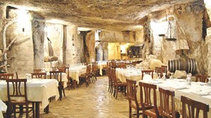 Un restaurant aux murs de pierre et aux tables dressées pour le repas.