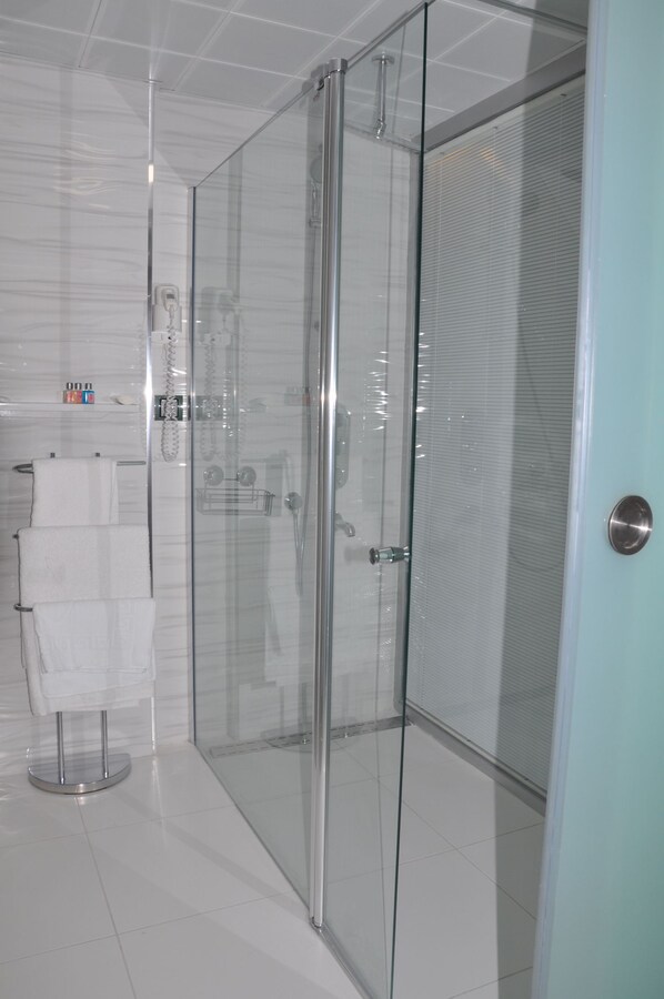 A modern bathroom with a glass shower enclosure, a towel rack, and a toilet.