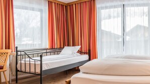 A hotel room with two beds, a wooden desk, and a chair. - B&B Oberreiter (Fusch an der Grossglocknerstrasse)