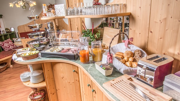 A breakfast buffet with various food items, including pastries and beverages, arranged on wooden tables and shelves. - B&B Oberreiter (Fusch an der Grossglocknerstrasse)