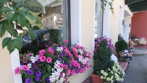 A window box with a variety of flowers, a small potted plant, and a bench outside a building. - B&B Oberreiter (Fusch an der Grossglocknerstrasse)