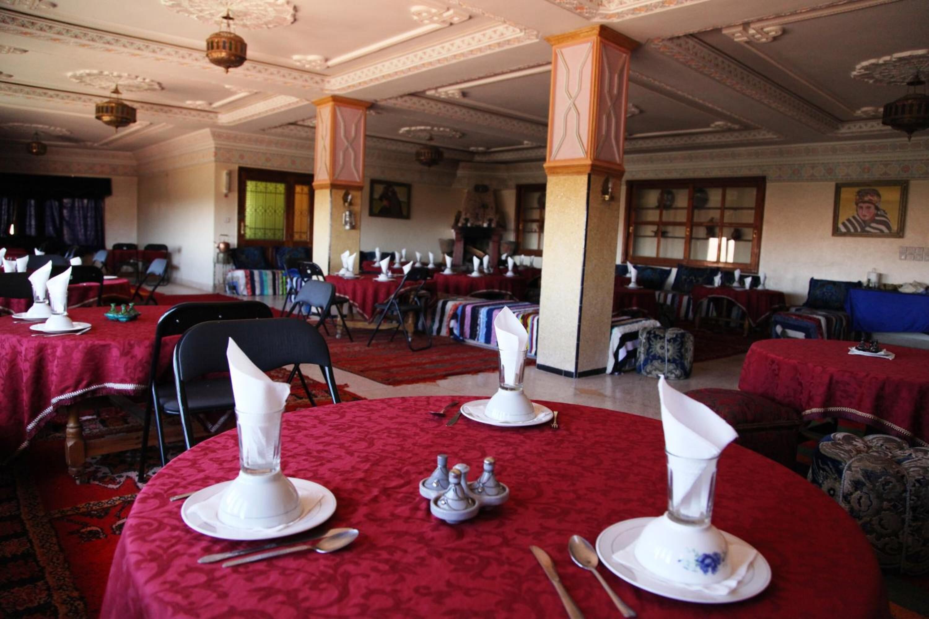 Un salón de banquetes con mesas redondas dispuestas para un evento formal, con manteles blancos, cubiertos y servilletas.