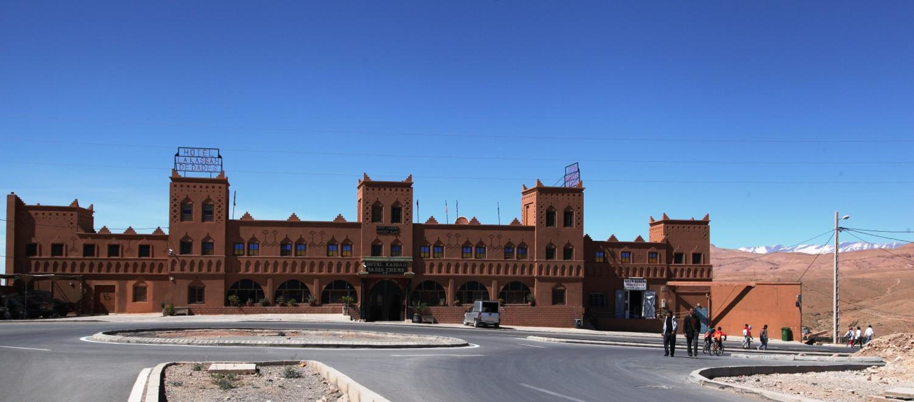 Un grand bâtiment à plusieurs étages, doté de fenêtres en arc de cercle et d’une entrée centrale, qui ressemble probablement à un hôtel ou à un bâtiment public.