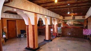 A lobby with a tiled floor, wooden columns, a reception desk, and a large painting on the wall. - La Kasbah De Dades (Boumalne Dades)