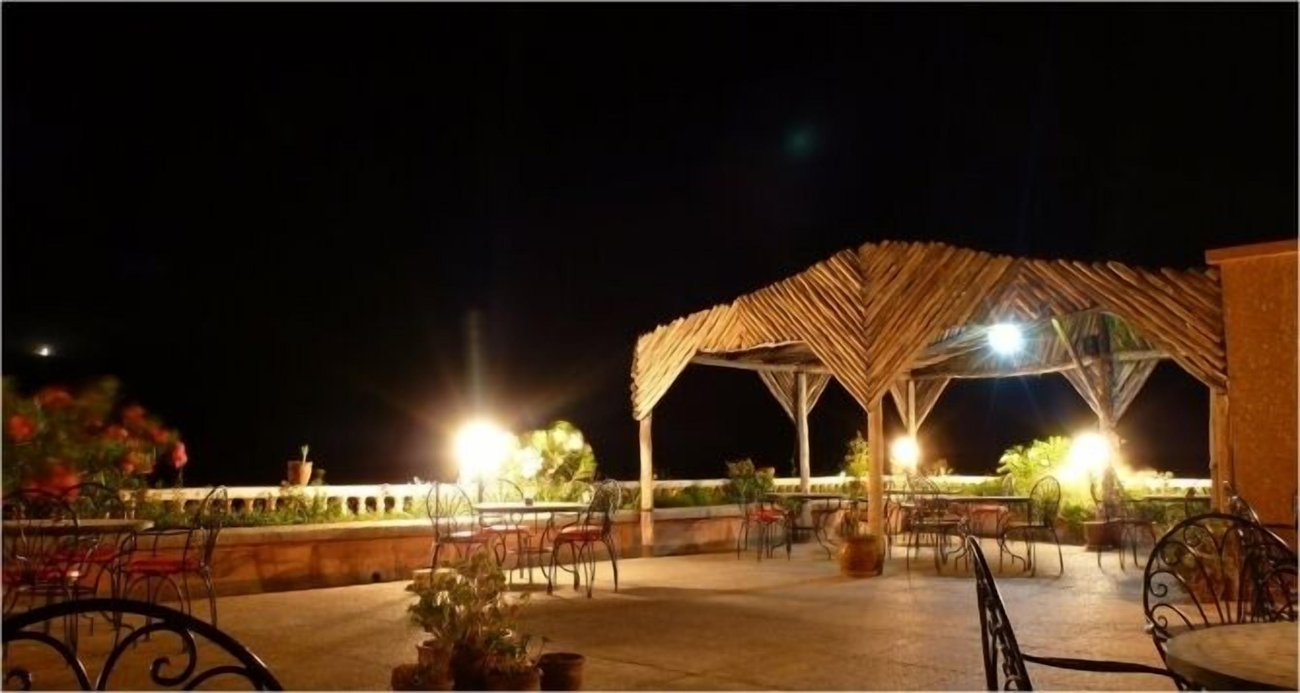 Un espacio de patio al aire libre con una estructura de techo de paja, mesas y sillas.