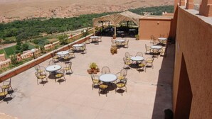 A rooftop terrace with outdoor seating and a view of a mountainous landscape. - La Kasbah De Dades (Boumalne Dades)