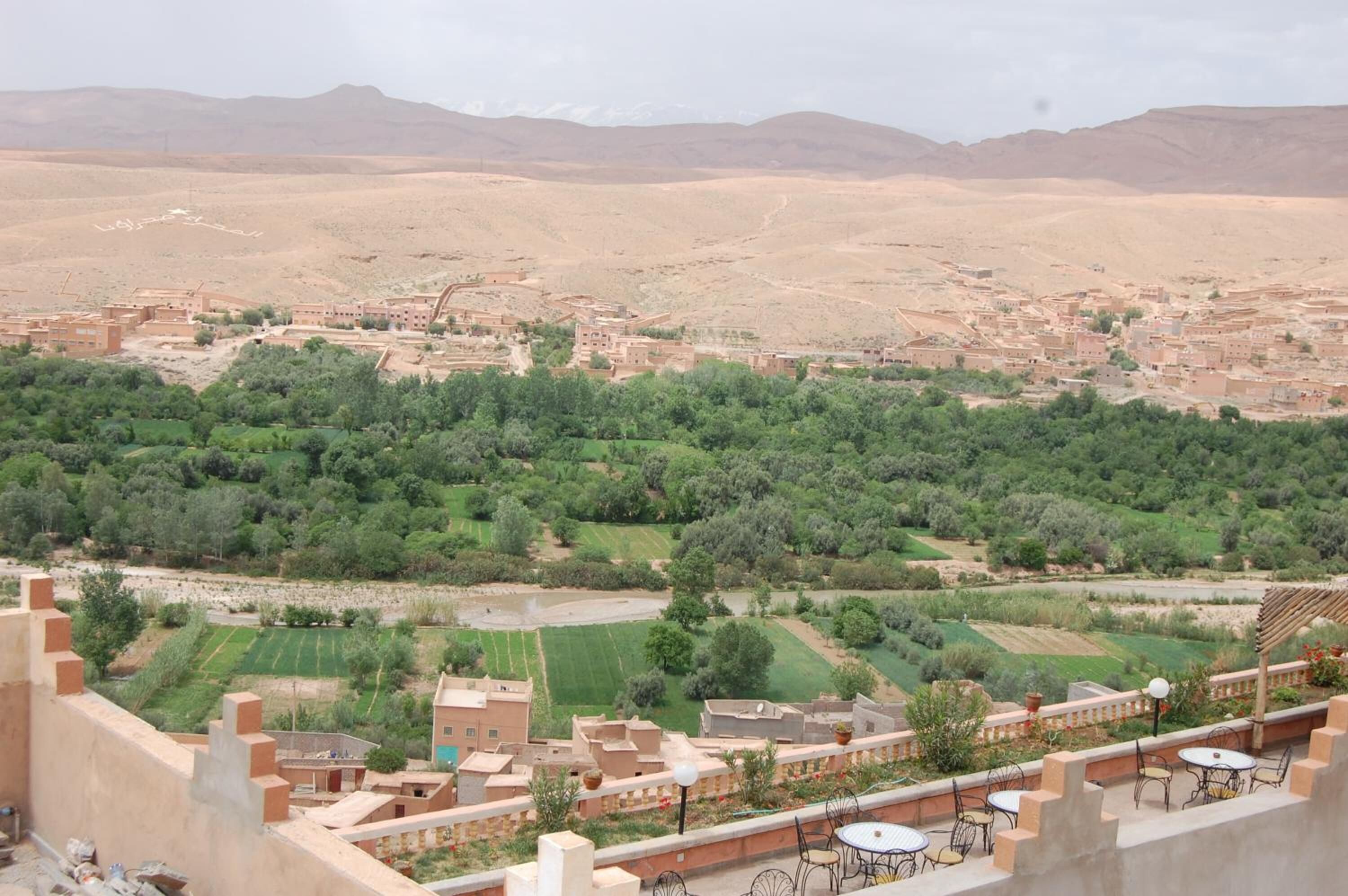 Vista de un paisaje desértico con un pueblo y campos verdes.